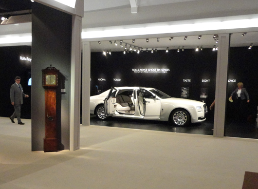 Ancient and modern — a long case clock stands opposite a Rolls Royce Ghost at the 21012 Masterpiece fair in Chelsea, London this week. Even the car's trunk has a lambswool lining to 'cosset' custom luggage. Photo Auction Central News.